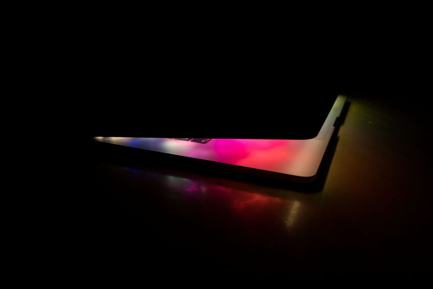 Uno schermo di laptop illuminato su una scrivania di legno scuro.
