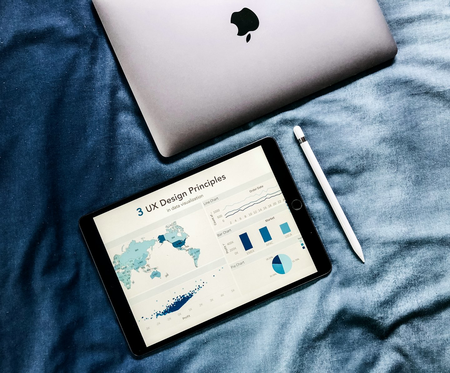 Tablet che mostra visualizzazioni di dati con stilo e laptop.